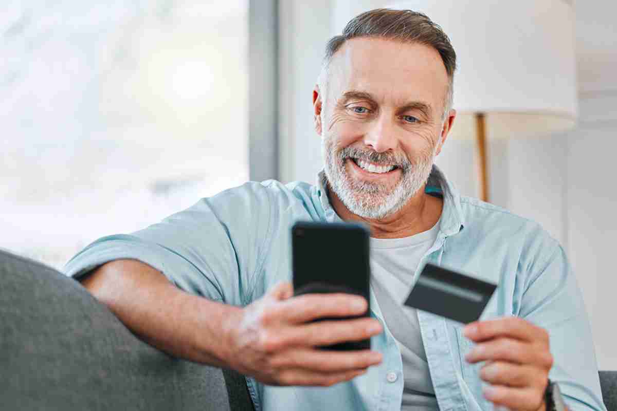 © K Davis/peopleimages.com - stock.adobe.com Mann mit Smartphone und Kredikarte